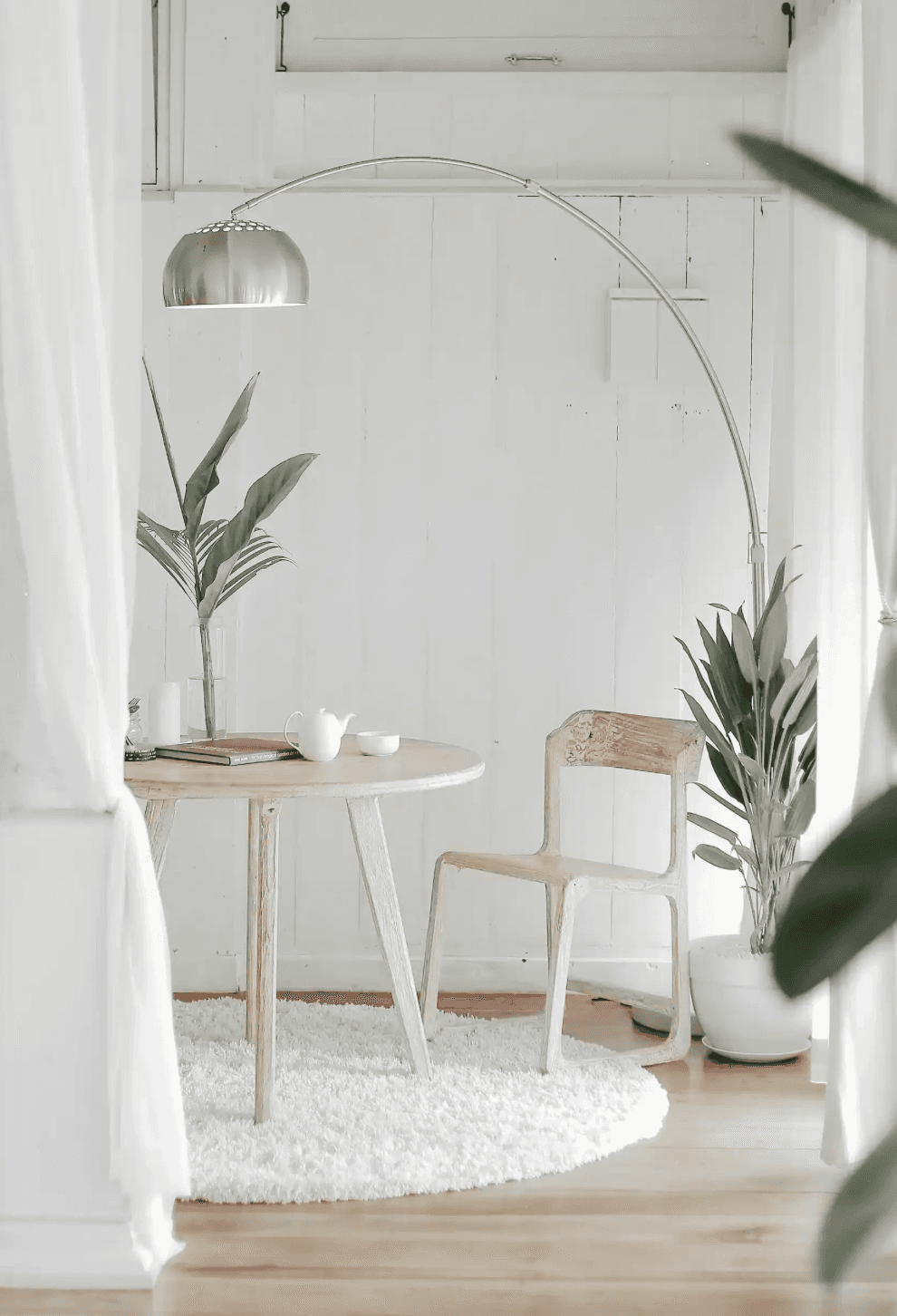 A calm, light-filled therapy space with an arc lamp, a small table, and plants