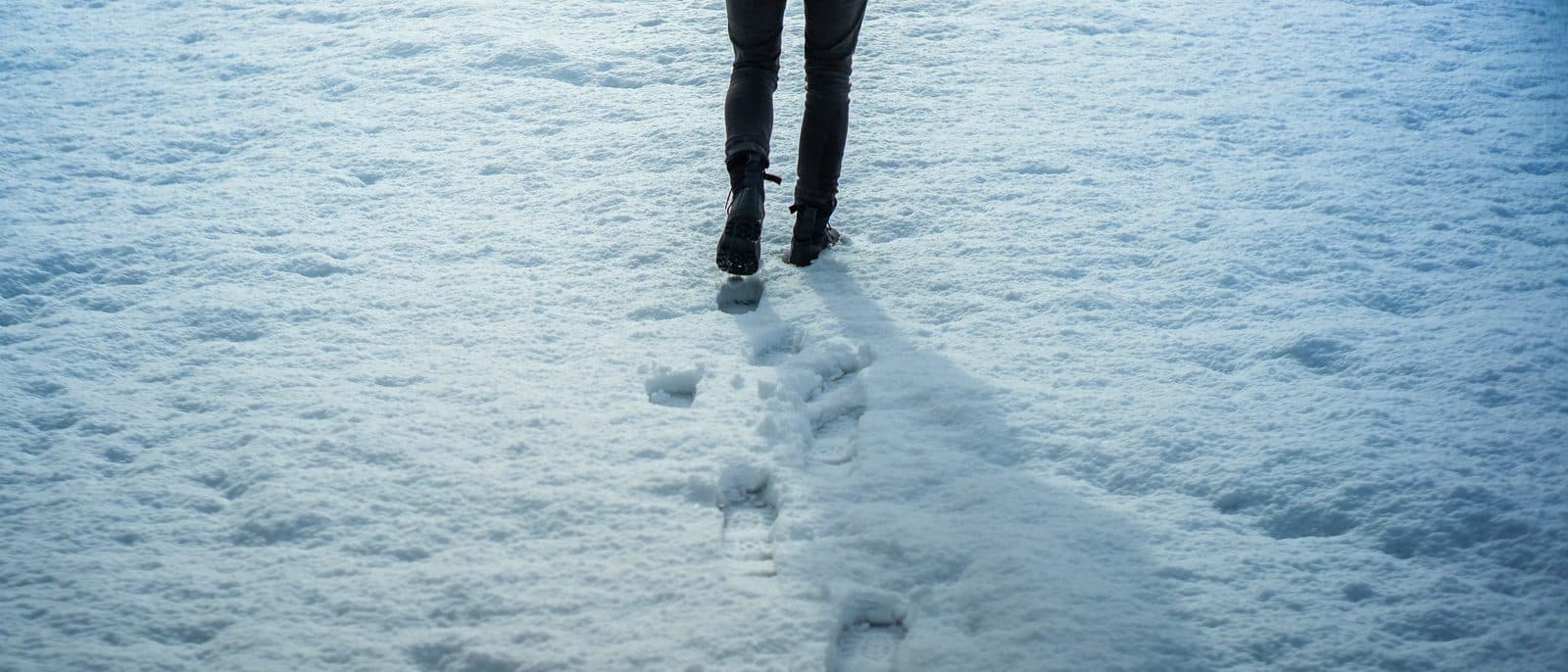 A single set of footprints leading away across deep, untouched snow
