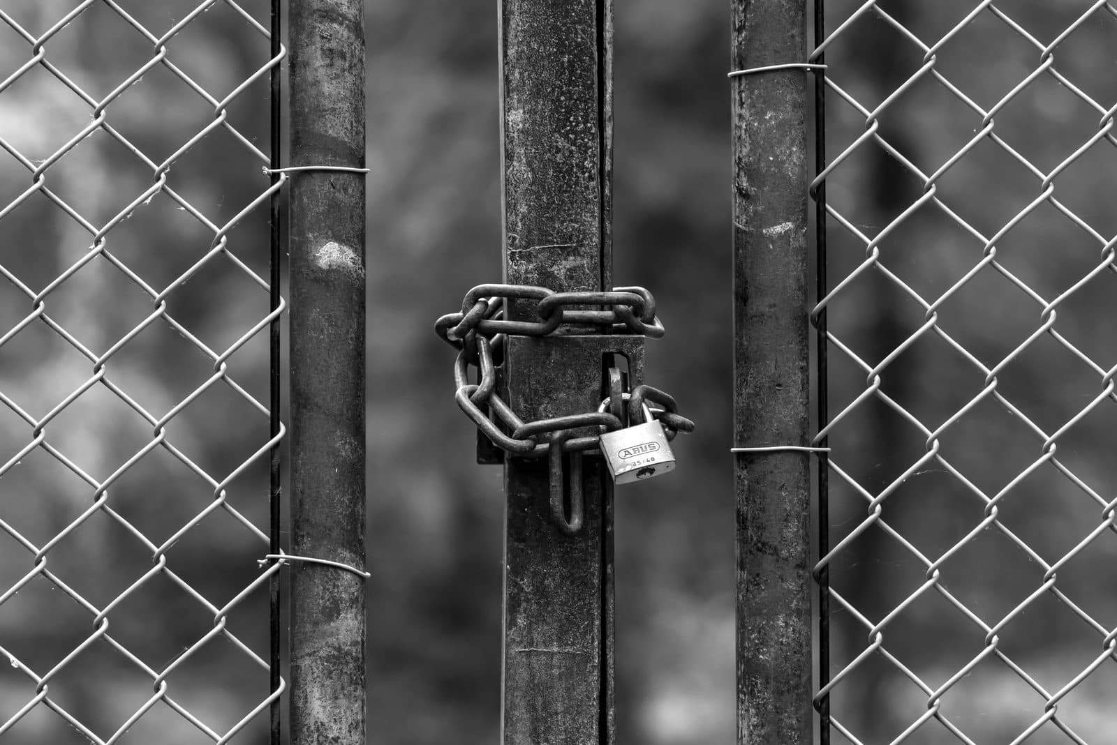 A heavy padlock and chain securing a chain-link gate