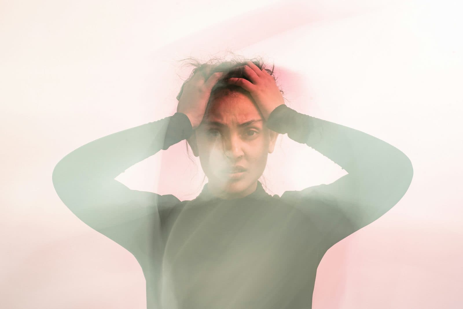 A person holding their head in both hands, their features blurred by motion