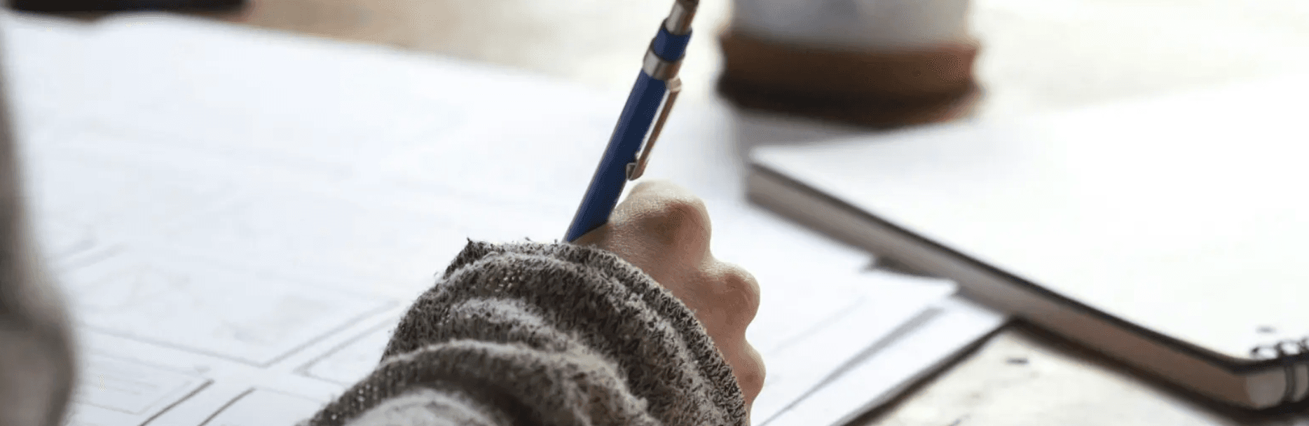 A quiet moment writing by hand at a sunlit desk — taking the first step toward therapy