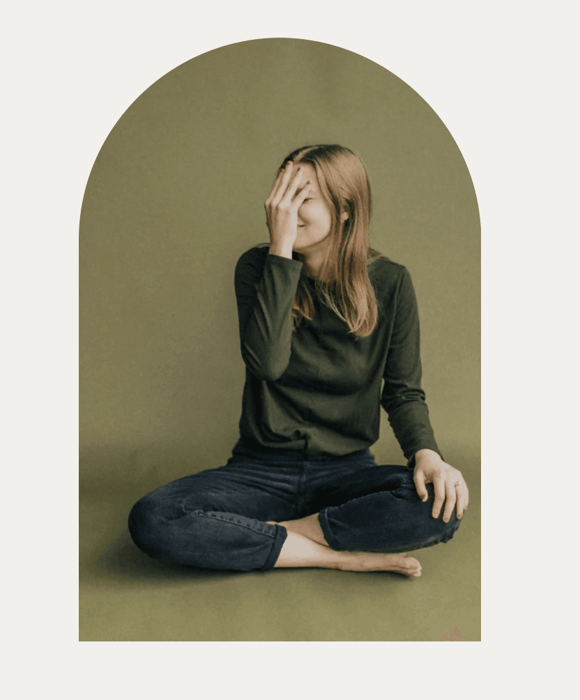 A person seated with a hand covering their face