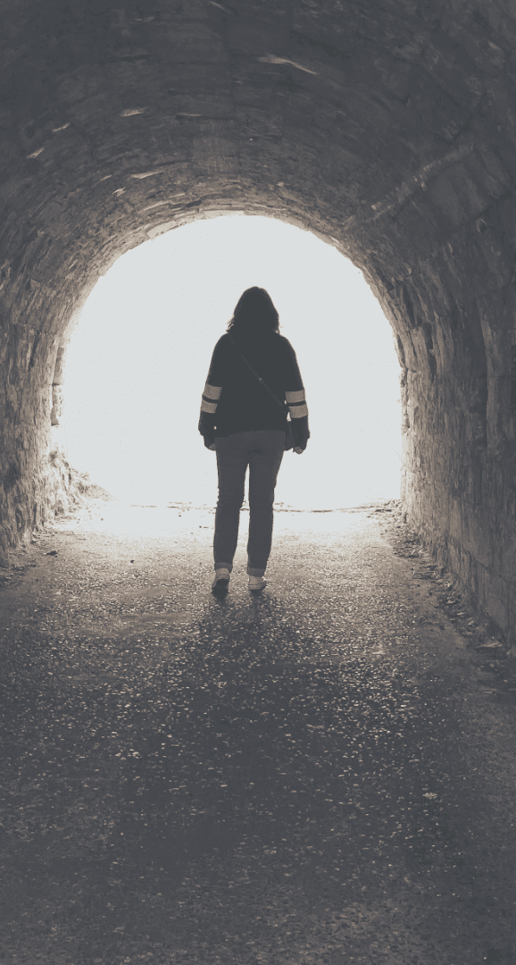 A person walking through a tunnel toward the light at the end — a metaphor for moving through religious harm toward healing