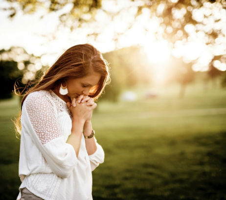 A person at sunset, hands clasped in reflection